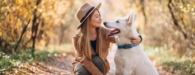 Kvinde i skov med hund med bluetooth GPS-tracker fra Tractive